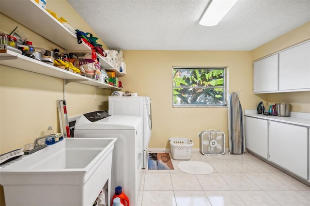 clothes washing area with light tile floors, a textured ceiling, separate washer and dryer, and sink