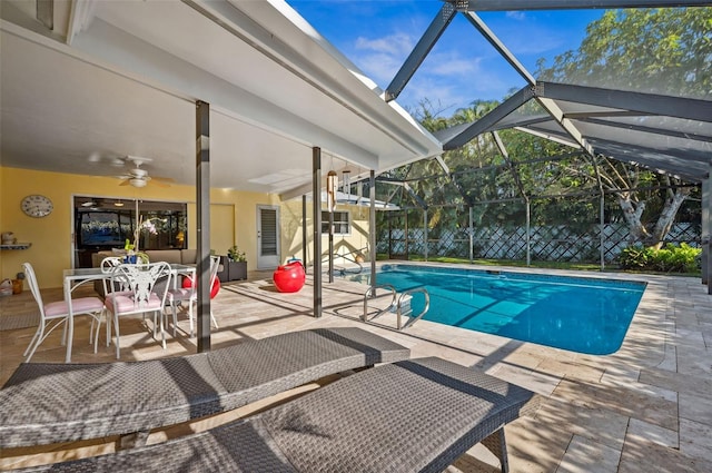 view of pool with a patio, glass enclosure, and ceiling fan