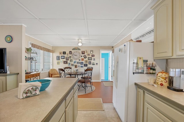 kitchen featuring white fridge, cream cabinets, a paneled ceiling, and light tile floors