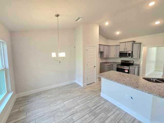 kitchen with gray cabinetry, light stone counters, stainless steel appliances, hanging light fixtures, and lofted ceiling