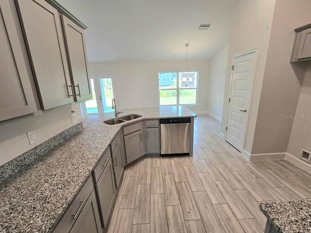 kitchen with light stone counters, dishwasher, sink, gray cabinetry, and light wood-type flooring