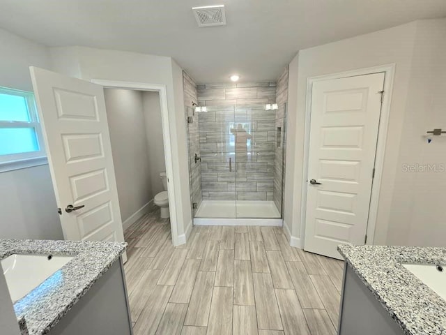 bathroom featuring toilet, vanity, and a shower with shower door