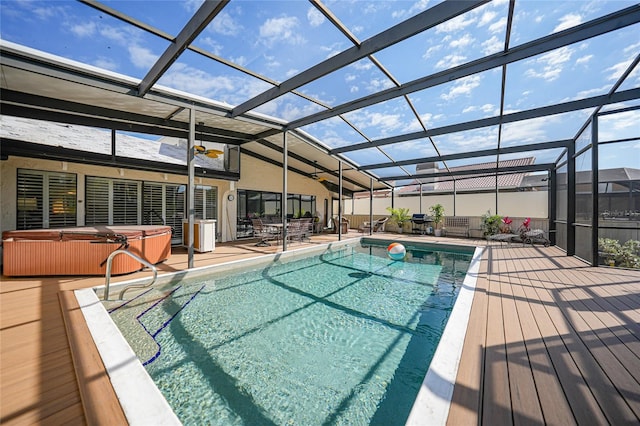 view of swimming pool featuring glass enclosure, a hot tub, and a patio area