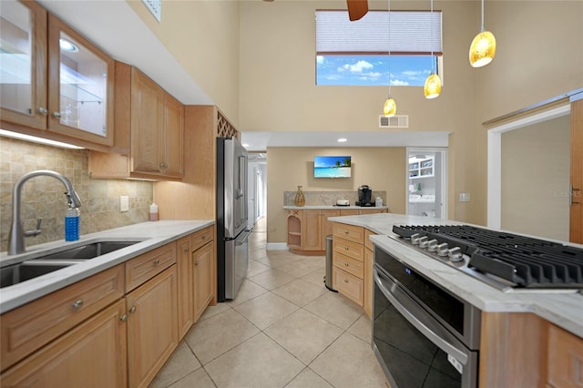 kitchen with sink, stainless steel appliances, light tile flooring, and a towering ceiling