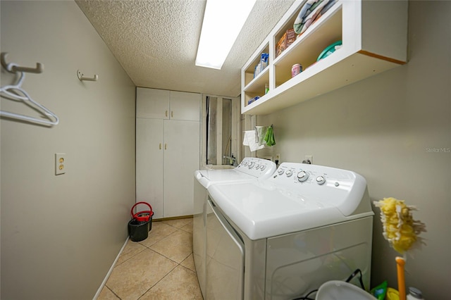 washroom featuring light tile floors, hookup for a washing machine, washing machine and clothes dryer, and a textured ceiling