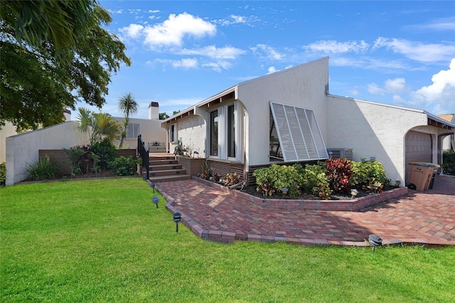 view of home's exterior with a patio area, a garage, a yard, and central AC unit