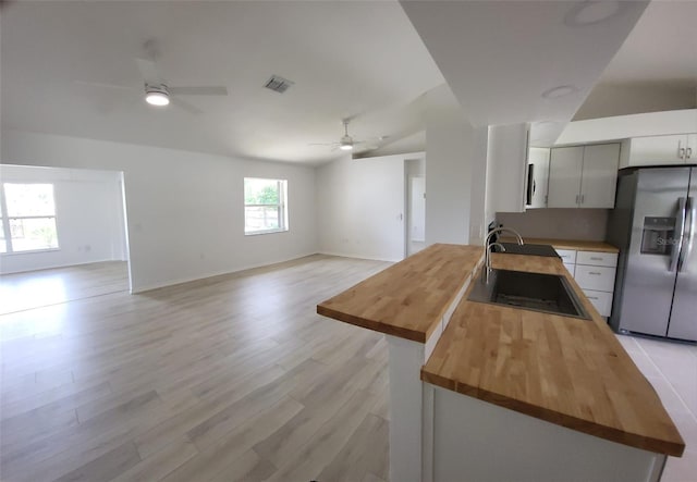 kitchen with ceiling fan, stainless steel fridge, light wood-type flooring, and butcher block counters