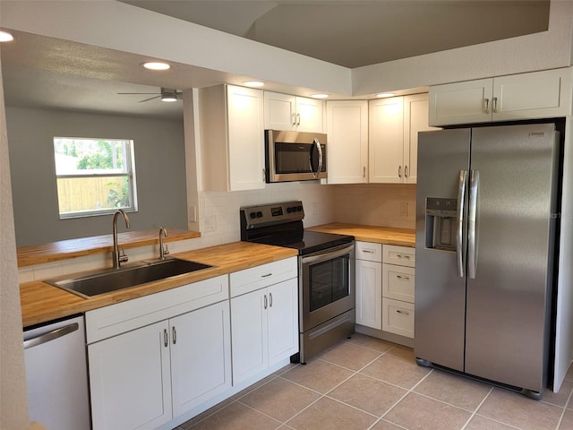 kitchen with white cabinets, appliances with stainless steel finishes, butcher block countertops, sink, and ceiling fan