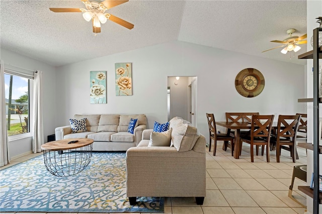 living room featuring vaulted ceiling, ceiling fan, light tile floors, and a textured ceiling