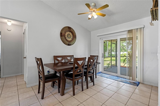 dining area featuring lofted ceiling, ceiling fan, light tile floors, and a textured ceiling