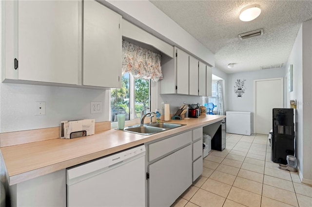 kitchen featuring a textured ceiling, sink, white dishwasher, and white cabinetry