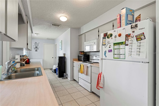 kitchen featuring light tile floors, a textured ceiling, white appliances, and sink