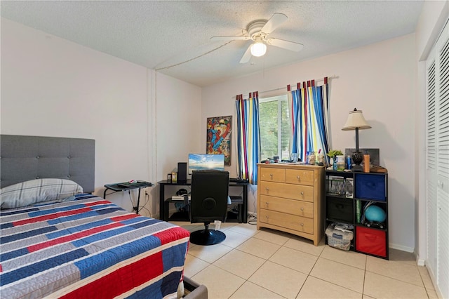 tiled bedroom with ceiling fan, a closet, and a textured ceiling