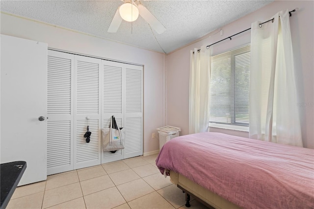 bedroom with a textured ceiling, ceiling fan, light tile floors, and a closet