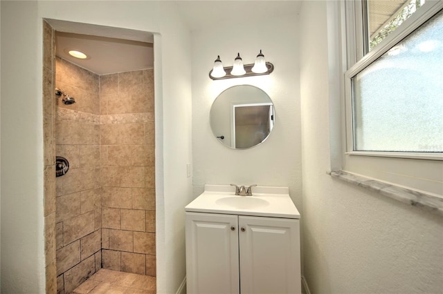 bathroom featuring tiled shower and vanity