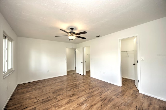 unfurnished bedroom featuring hardwood / wood-style flooring, a closet, ceiling fan, and a spacious closet