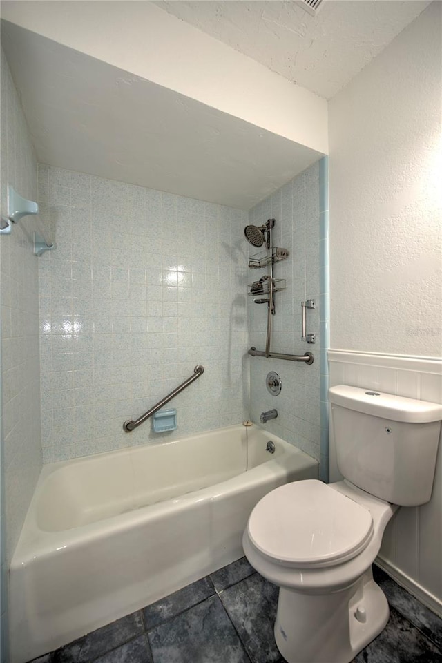 bathroom with tiled shower / bath combo, tile floors, and toilet