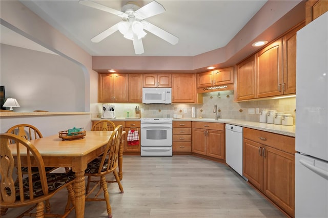 kitchen with white appliances, sink, light hardwood / wood-style flooring, ceiling fan, and tasteful backsplash