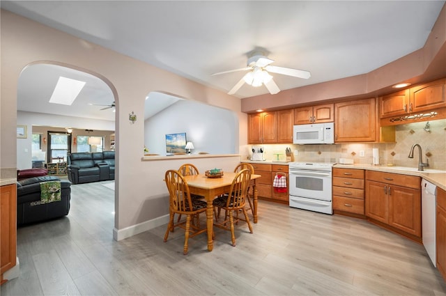 kitchen featuring white appliances, sink, ceiling fan, tasteful backsplash, and light hardwood / wood-style floors