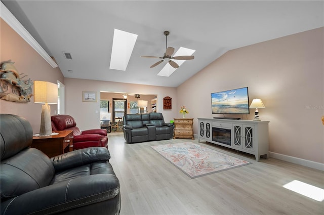 living room featuring ceiling fan, lofted ceiling with skylight, and light hardwood / wood-style flooring