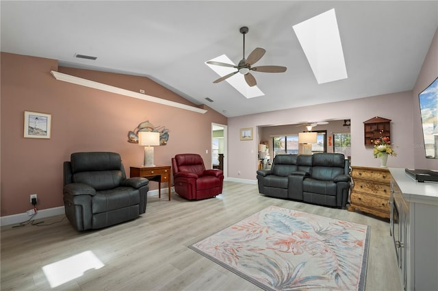 living room with ceiling fan, light hardwood / wood-style floors, and lofted ceiling with skylight