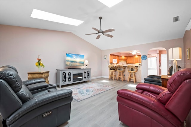 living room with ceiling fan, light hardwood / wood-style floors, and vaulted ceiling