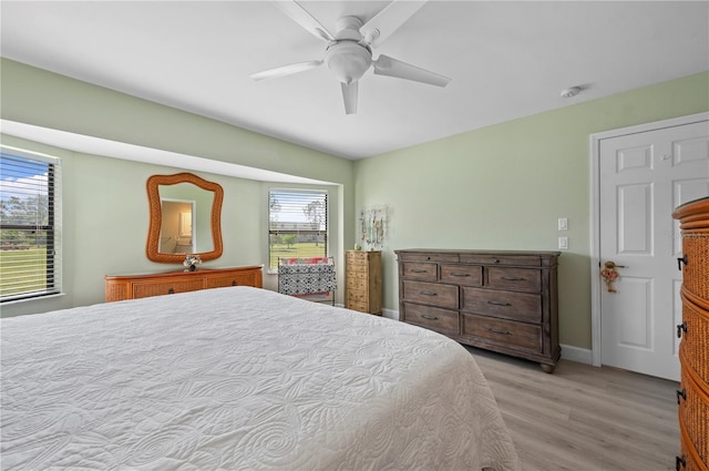 bedroom with light wood-type flooring, multiple windows, and ceiling fan