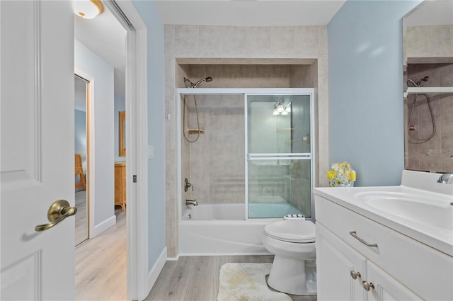 full bathroom with combined bath / shower with glass door, vanity, hardwood / wood-style flooring, and toilet