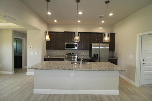 kitchen featuring appliances with stainless steel finishes, light hardwood / wood-style flooring, sink, and a center island with sink