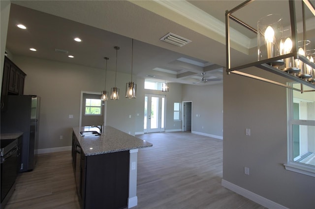 kitchen featuring an island with sink, coffered ceiling, french doors, dark stone countertops, and hardwood / wood-style flooring