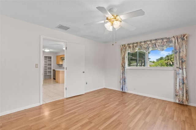 spare room with ceiling fan, light hardwood / wood-style floors, and a textured ceiling