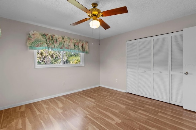 unfurnished bedroom featuring wood-type flooring, a textured ceiling, a closet, and ceiling fan