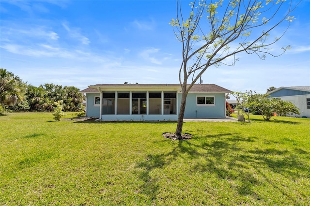 back of property with a lawn, a patio area, and a sunroom