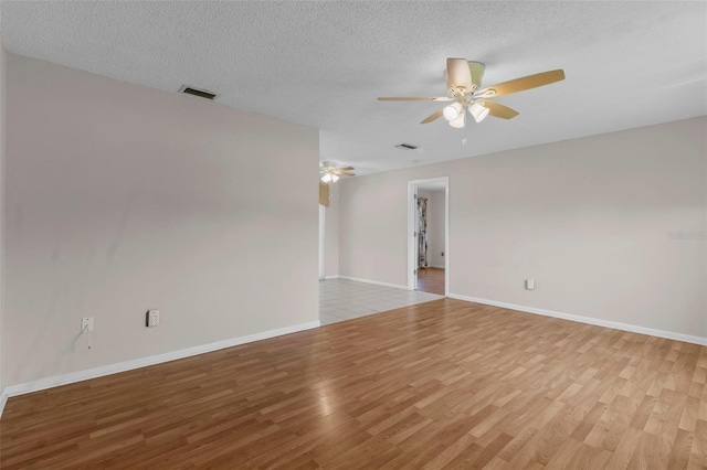 spare room featuring ceiling fan, light wood-type flooring, and a textured ceiling