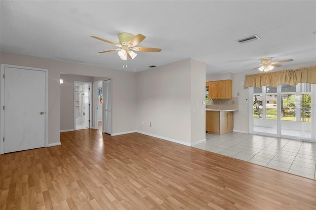 unfurnished living room featuring ceiling fan, light wood-type flooring, and a textured ceiling