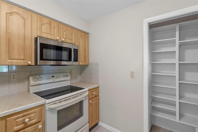 kitchen featuring light brown cabinets, backsplash, electric range, a textured ceiling, and light tile patterned flooring