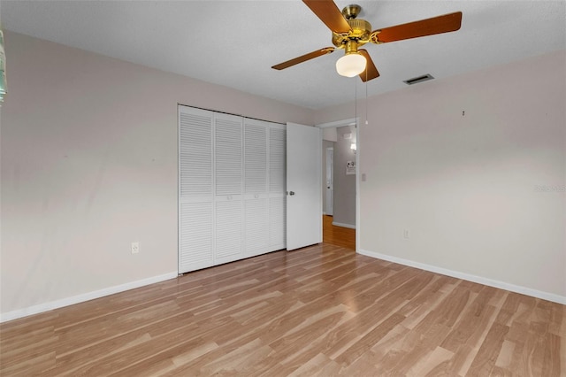 unfurnished bedroom featuring ceiling fan, light wood-type flooring, a textured ceiling, and a closet