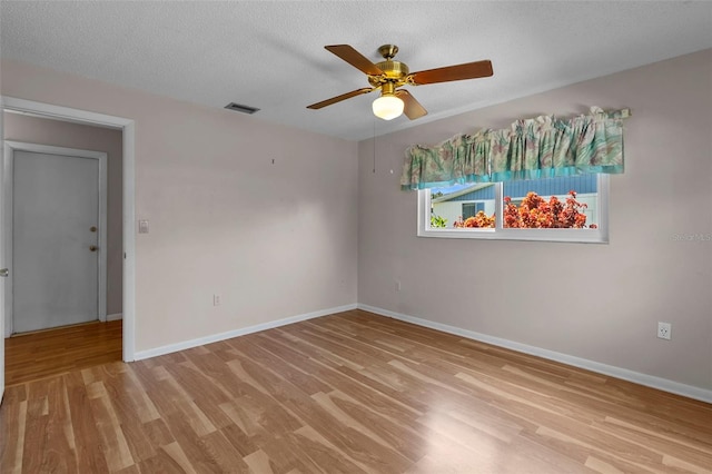 empty room featuring ceiling fan, light wood-type flooring, and a textured ceiling