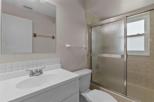 full bathroom with combined bath / shower with glass door, vanity, and toilet