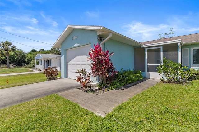 view of front of home with stucco siding, an attached garage, driveway, and a front lawn