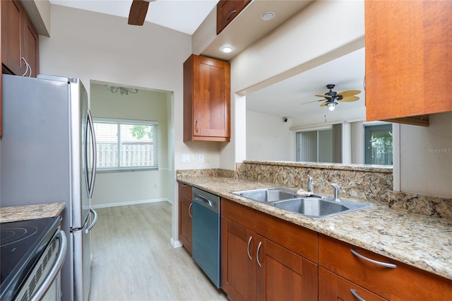 kitchen featuring light stone countertops, sink, ceiling fan, stainless steel appliances, and light hardwood / wood-style flooring