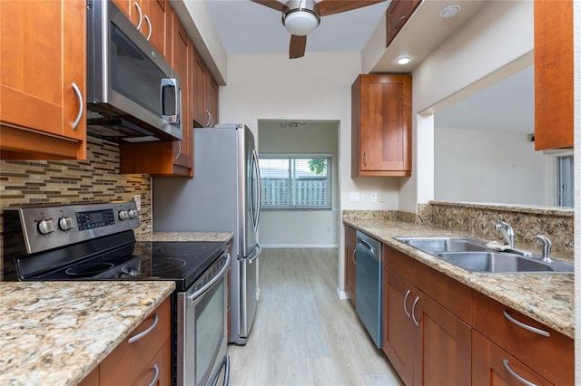 kitchen featuring tasteful backsplash, sink, stainless steel appliances, light stone counters, and light hardwood / wood-style flooring