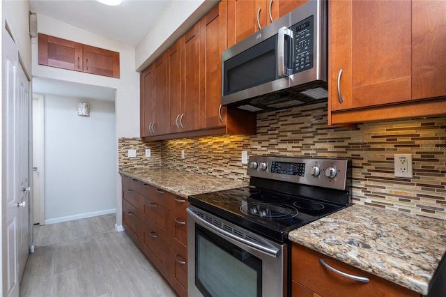 kitchen featuring light hardwood / wood-style floors, stainless steel appliances, light stone countertops, and decorative backsplash