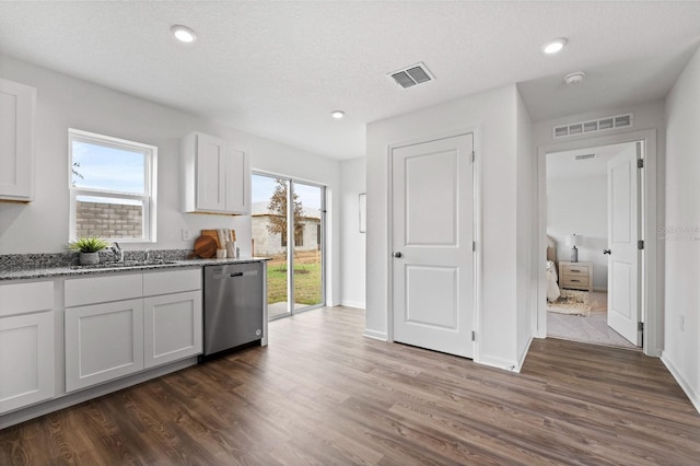 kitchen with a healthy amount of sunlight, stainless steel dishwasher, dark hardwood / wood-style floors, and white cabinets