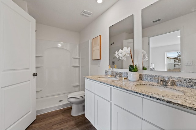 bathroom featuring a shower, vanity, toilet, and hardwood / wood-style floors