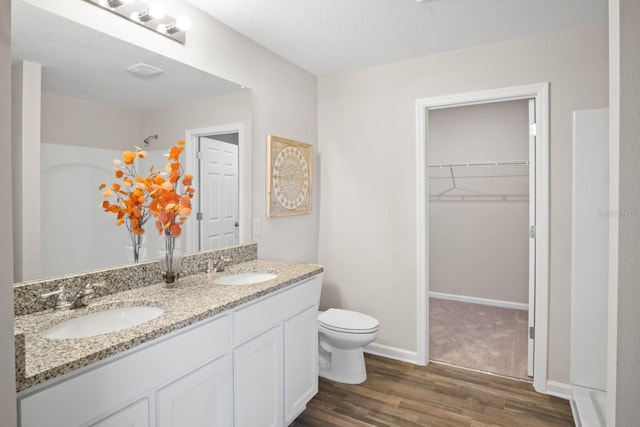 bathroom featuring wood-type flooring, vanity, toilet, and a textured ceiling