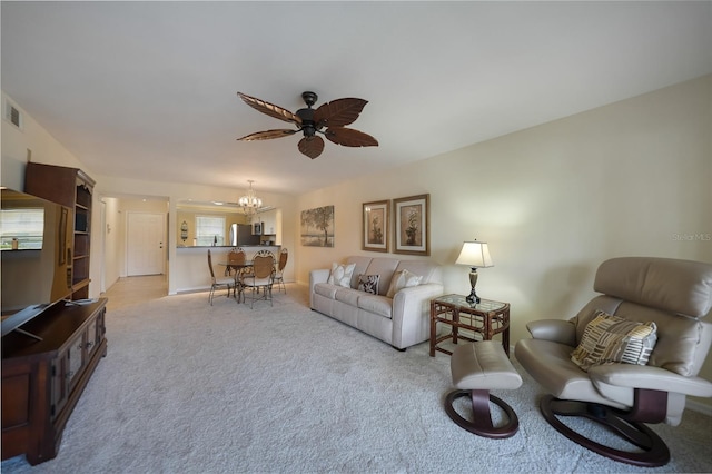 living room featuring light colored carpet and ceiling fan with notable chandelier