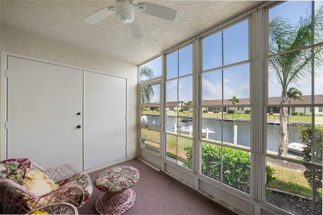 sunroom featuring a water view and ceiling fan