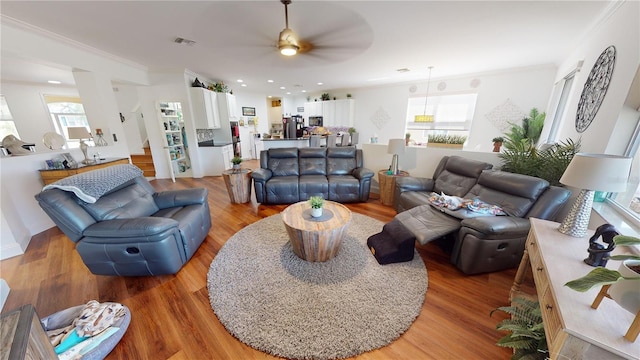 living room featuring wood-type flooring, ornamental molding, and ceiling fan