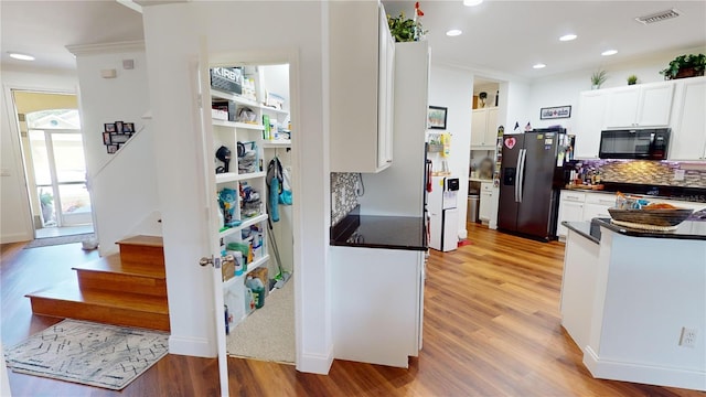 kitchen with stainless steel refrigerator with ice dispenser, light wood-type flooring, white cabinets, and decorative backsplash